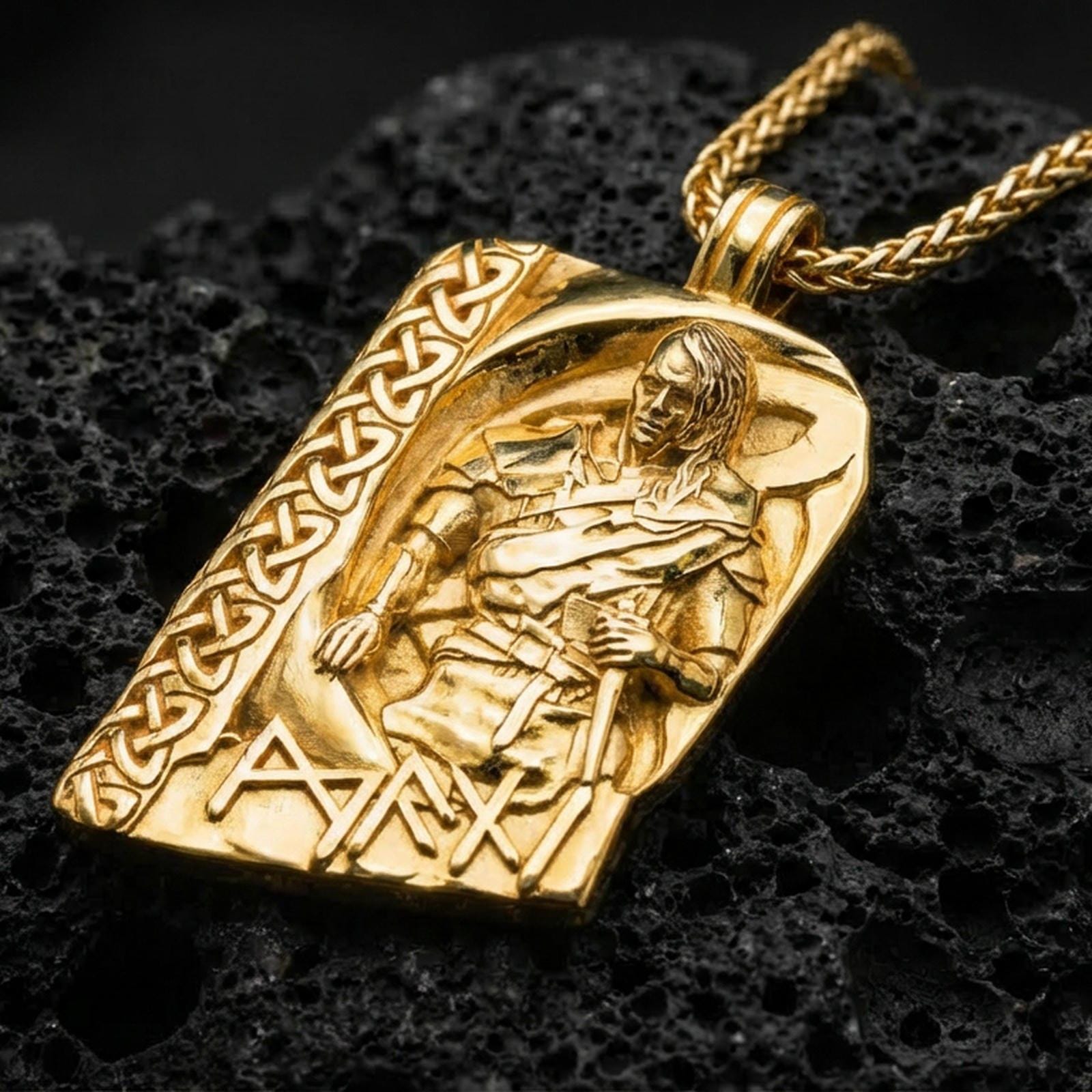 Gold plated Norse moon god pendant necklace on textured volcanic rock, premium close-up with warm reflective shine across the warrior figure, raised rune accents, and detailed knotwork frame.