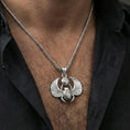 Load image into Gallery viewer, Polished silver winged scarab beetle pendant necklace worn on the neck, clean lifestyle wear shot capturing bright shine and the detailed Eye of Ra and wing relief in natural light.
