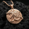 Load image into Gallery viewer, Rose gold plated Anubis medallion pendant necklace on textured volcanic rock, centered studio-style close-up showcasing soft rosy glow and intricate Egyptian jackal-and-hieroglyph detailing.
