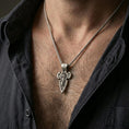Load image into Gallery viewer, Oxidized Saint Michael cross pendant with winged archangel figure worn on the neck in a lifestyle jewelry shot, styled against the chest for a bold and protective look
