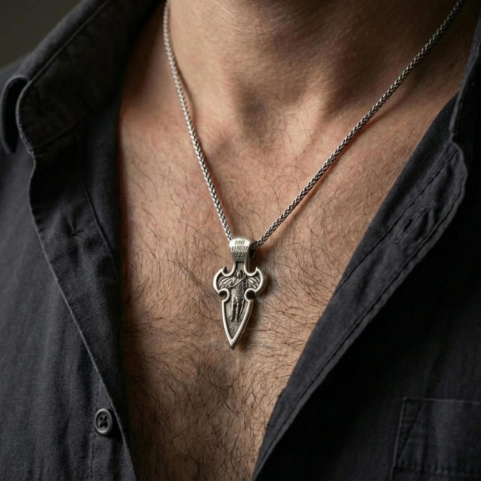 Oxidized Saint Michael cross pendant with winged archangel figure worn on the neck in a lifestyle jewelry shot, styled against the chest for a bold and protective look
