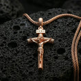 Load image into Gallery viewer, Rose gold plated Jesus cross pendant with sculpted corpus, INRI inscription, and slender crucifix form resting on volcanic rock in an elegant close-up product presentation
