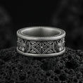 Load image into Gallery viewer, Oxidized fox band ring on textured volcanic rock, centered close-up highlighting the carved fox heads, ornate scrollwork, and deep antique shadowed contrast.
