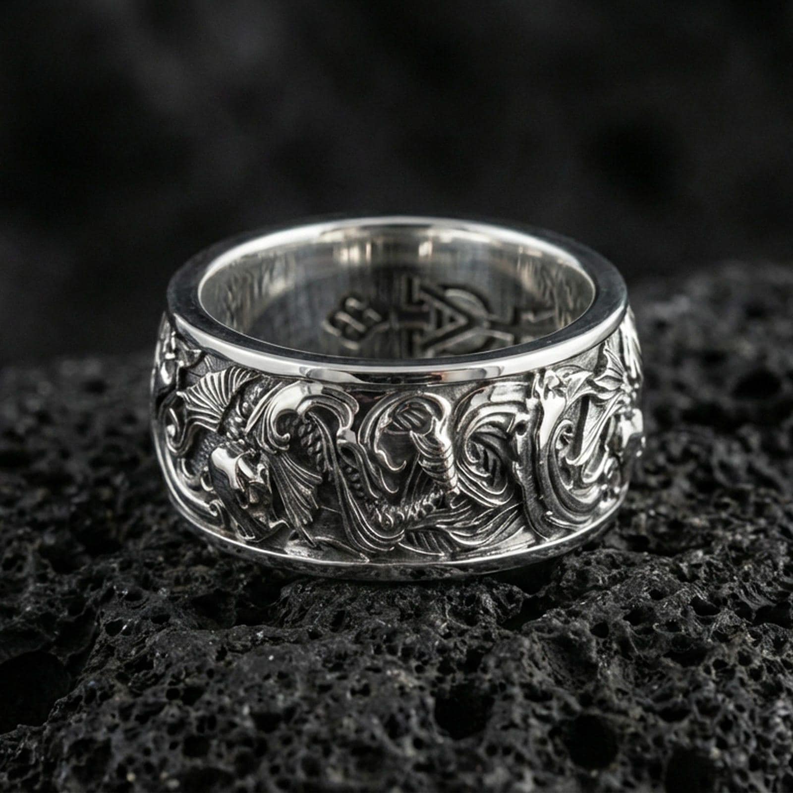 Polished silver koi fish band ring on textured volcanic rock, crisp macro product photo emphasizing clean edges, sharp engraved scales, and bright reflective highlights across the patterned band.