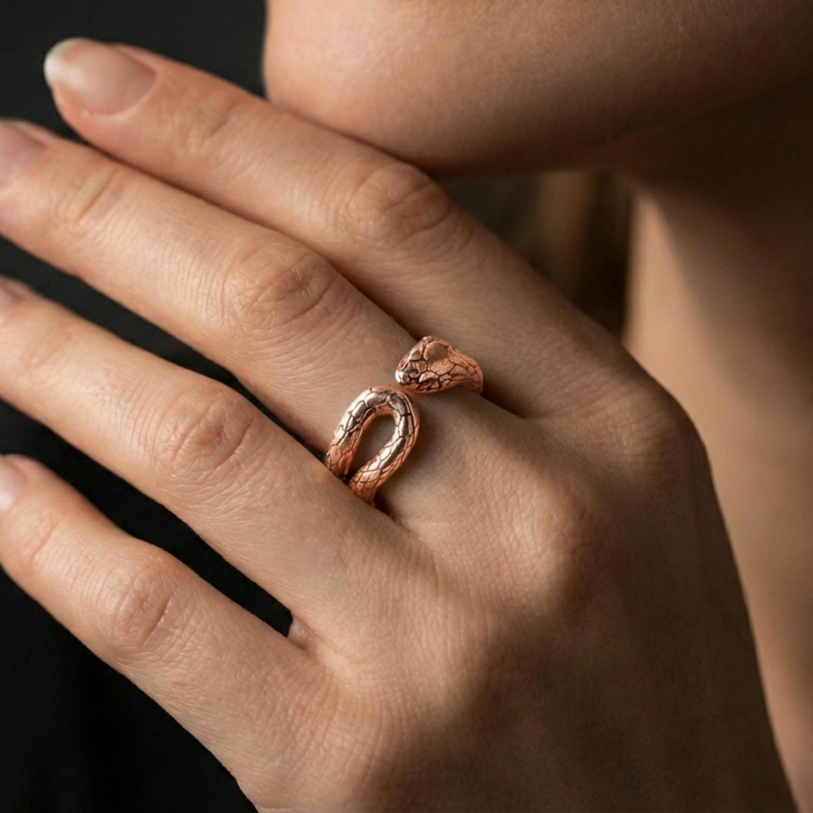 Rose gold plated snake wrap ring worn on a finger, lifestyle wear shot with elegant rosy shine and crisp snake scale detailing visible.