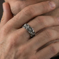 Load image into Gallery viewer, Oxidized floral band ring worn on a finger, lifestyle framing showing realistic scale and bold vintage contrast in a natural hand pose.
