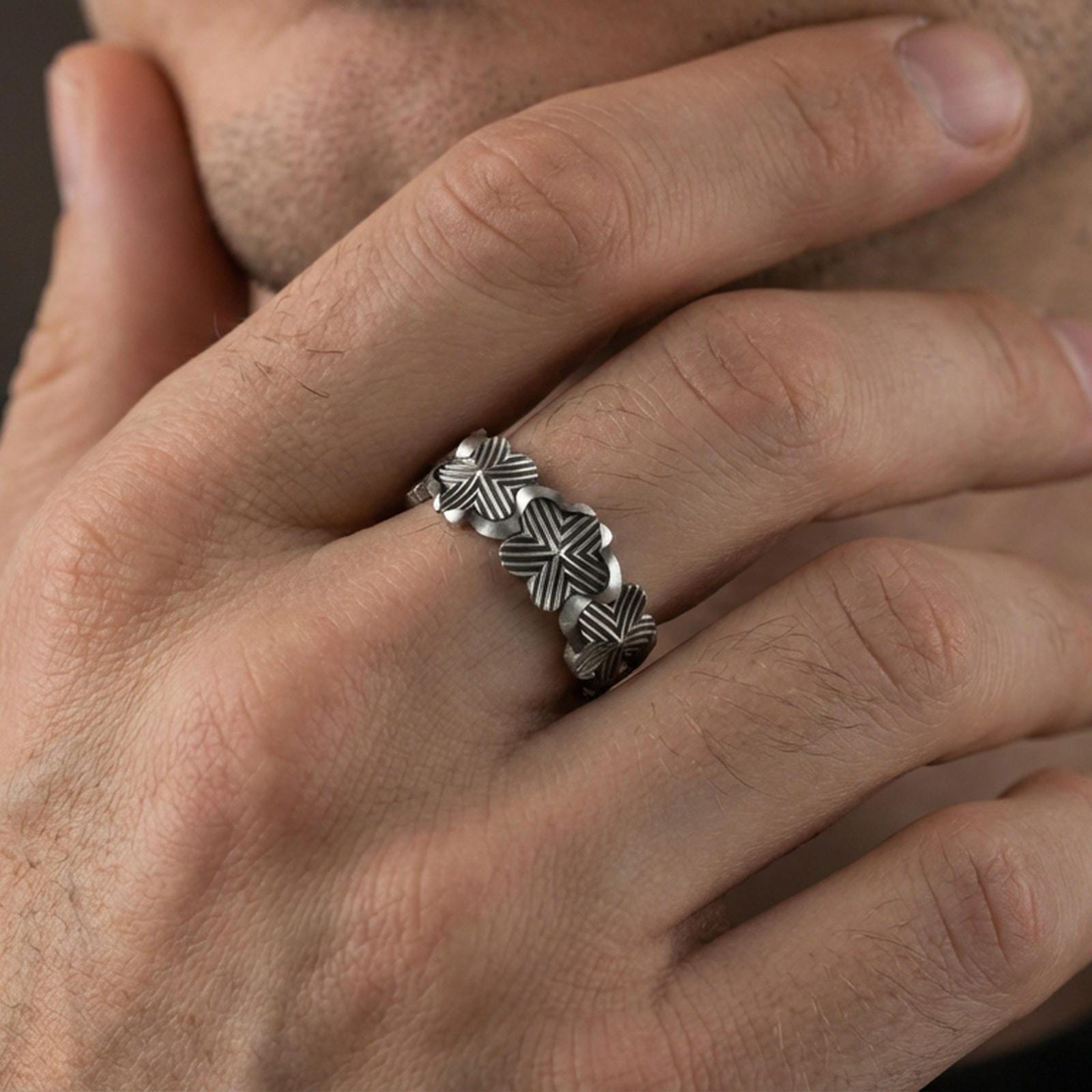 Oxidized floral band ring worn on a finger, lifestyle framing showing realistic scale and bold vintage contrast in a natural hand pose.