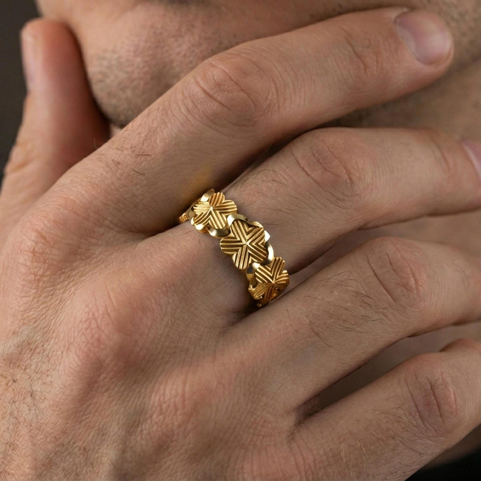 Gold plated floral band ring worn on a finger, lifestyle photo featuring warm tone finish and strong statement band presence.