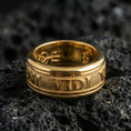 Load image into Gallery viewer, Gold plated Veni Vidi Vici spinner ring on textured volcanic rock, premium close-up with warm reflective shine across the rotating band and bold Roman-style lettering.
