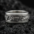 Load image into Gallery viewer, Oxidized wolf head band ring on textured volcanic rock, centered close-up highlighting the carved wolf motifs, flowing fur texture, and deep antique shadowed contrast.
