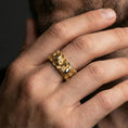 Load image into Gallery viewer, Gold plated skull and floral band ring worn on a finger, lifestyle photo featuring warm tone finish and strong statement band presence.
