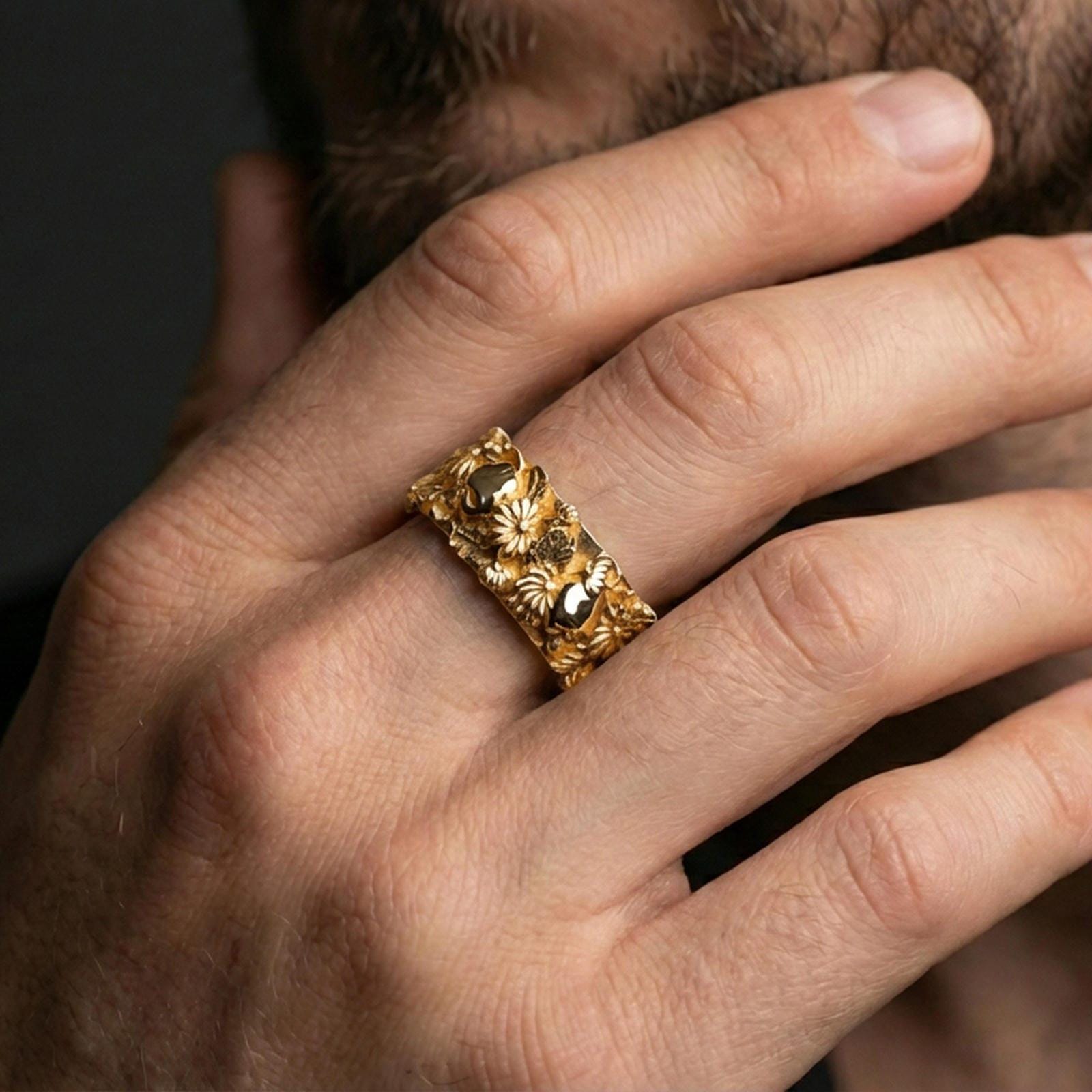 Gold plated skull and floral band ring worn on a finger, lifestyle photo featuring warm tone finish and strong statement band presence.