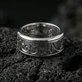 Load image into Gallery viewer, Polished silver Egyptian symbols band ring on textured volcanic rock, crisp macro product photo emphasizing clean edges, sharp hieroglyph engraving, and bright reflective highlights across the band.
