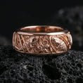 Load image into Gallery viewer, Rose gold plated koi fish and lotus band ring on textured volcanic rock, centered studio-style close-up showcasing soft rosy glow and intricate koi-and-lotus detailing with a refined finish.
