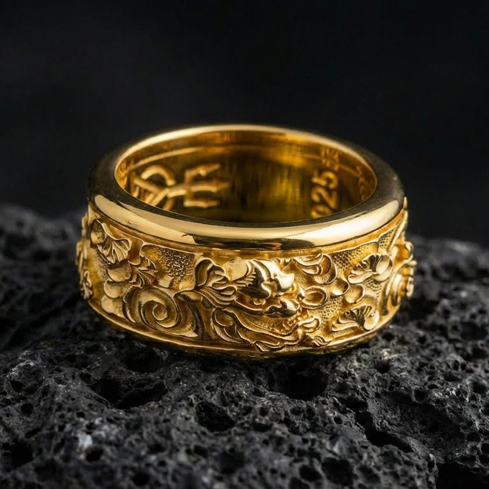 Gold plated oriental dragon band ring on textured volcanic rock, premium close-up with warm reflective shine across the dragon head, flowing cloud scrolls, and raised ornamental contours.