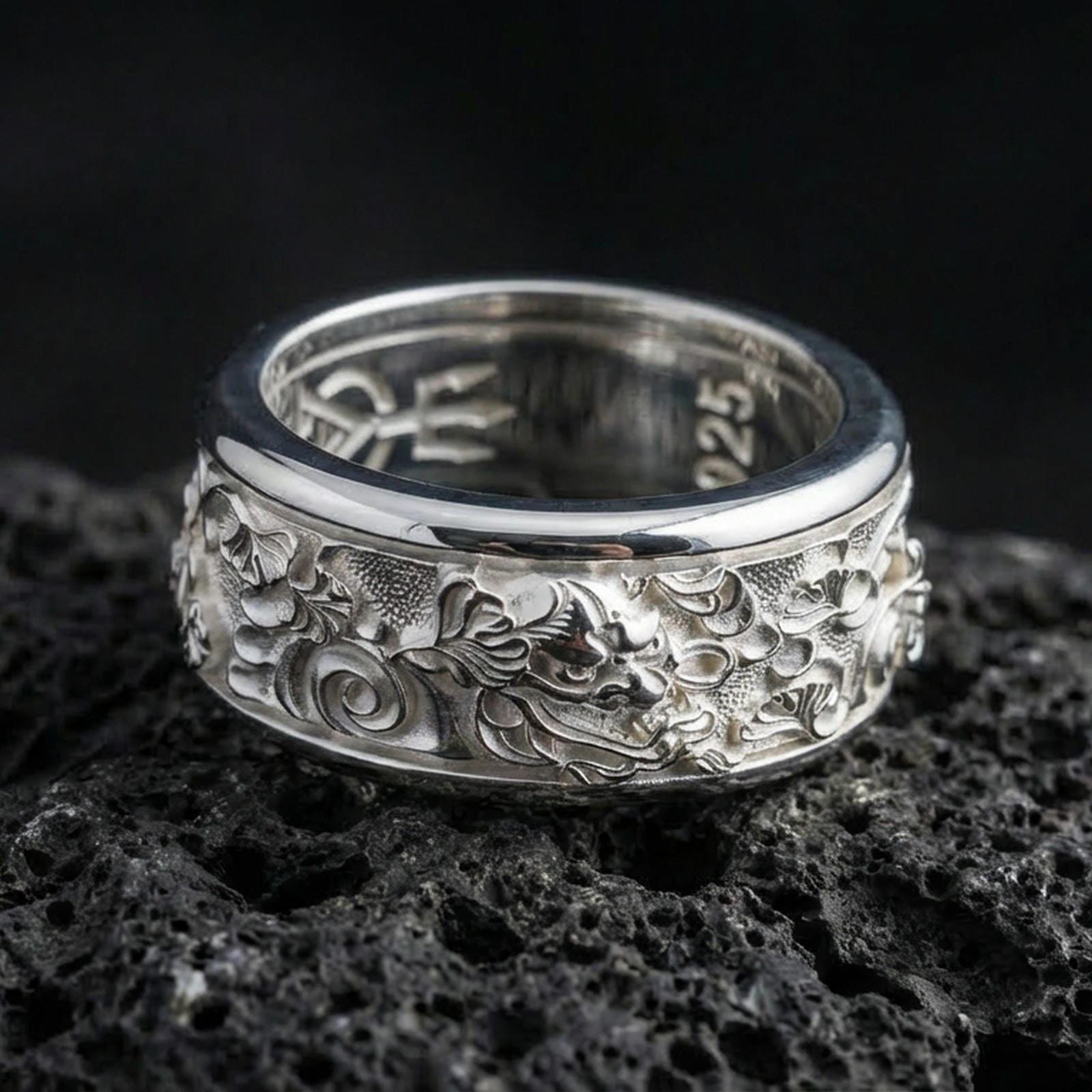 Polished silver oriental dragon band ring on textured volcanic rock, crisp macro product photo emphasizing clean edges, sharp dragon scales and facial detailing, and bright reflective highlights across the band.