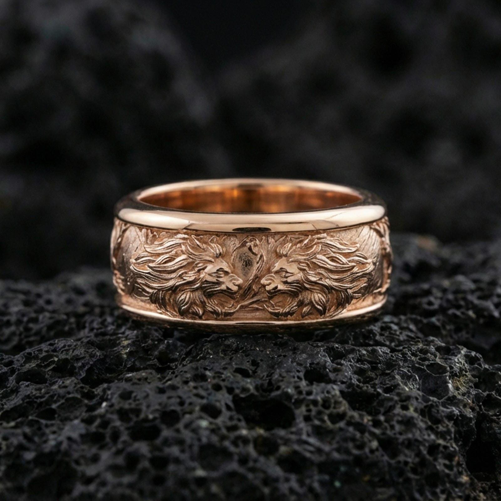 Rose gold plated twin lion band ring on textured volcanic rock, centered studio-style close-up showcasing soft rosy glow and intricate lion-and-mane detailing with a refined finish.