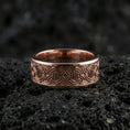 Load image into Gallery viewer, Rose gold plated geometric knotwork band ring on textured volcanic rock, centered studio-style close-up showcasing soft rosy glow and crisp knotwork detailing with a refined finish.
