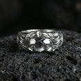 Load image into Gallery viewer, Polished silver face relief band ring on textured volcanic rock, crisp macro product photo emphasizing clean edges, smooth facial contours, and bright reflective highlights across the sculpted surface.
