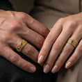 Load image into Gallery viewer, Gold plated ornate gemstone band ring worn on a finger, lifestyle image with warm tone shine and the blue-red-green stones standing out against the engraved pattern.
