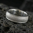 Load image into Gallery viewer, Polished silver woven texture band ring on textured volcanic rock, crisp studio macro emphasizing the basket-weave detail with clean bright reflections.
