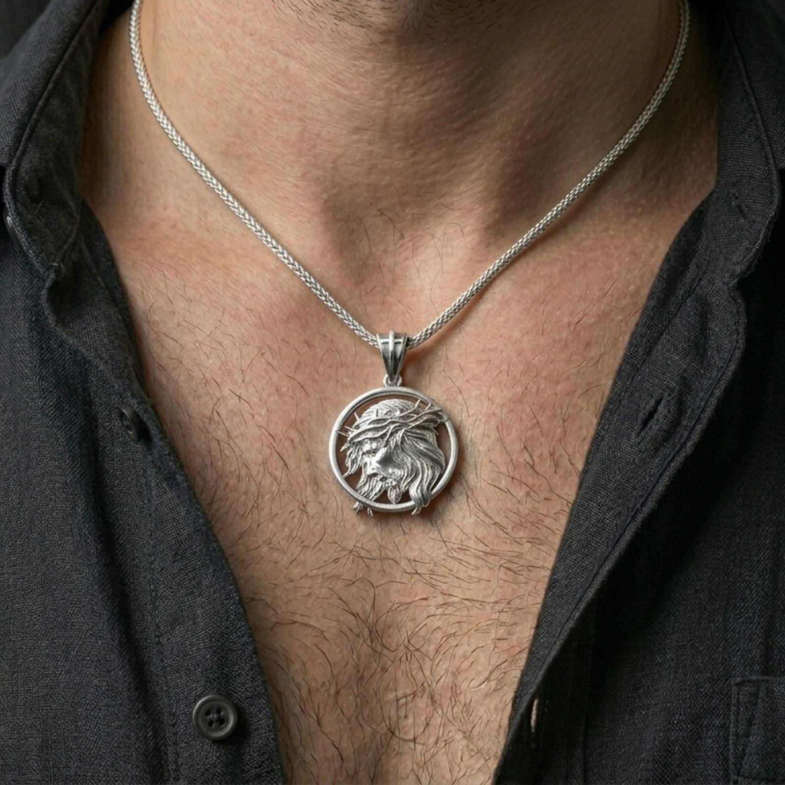 Polished silver Jesus medallion with side profile portrait and crown of thorns worn on the neck in a close lifestyle frame, highlighting the sculpted relief and circular design