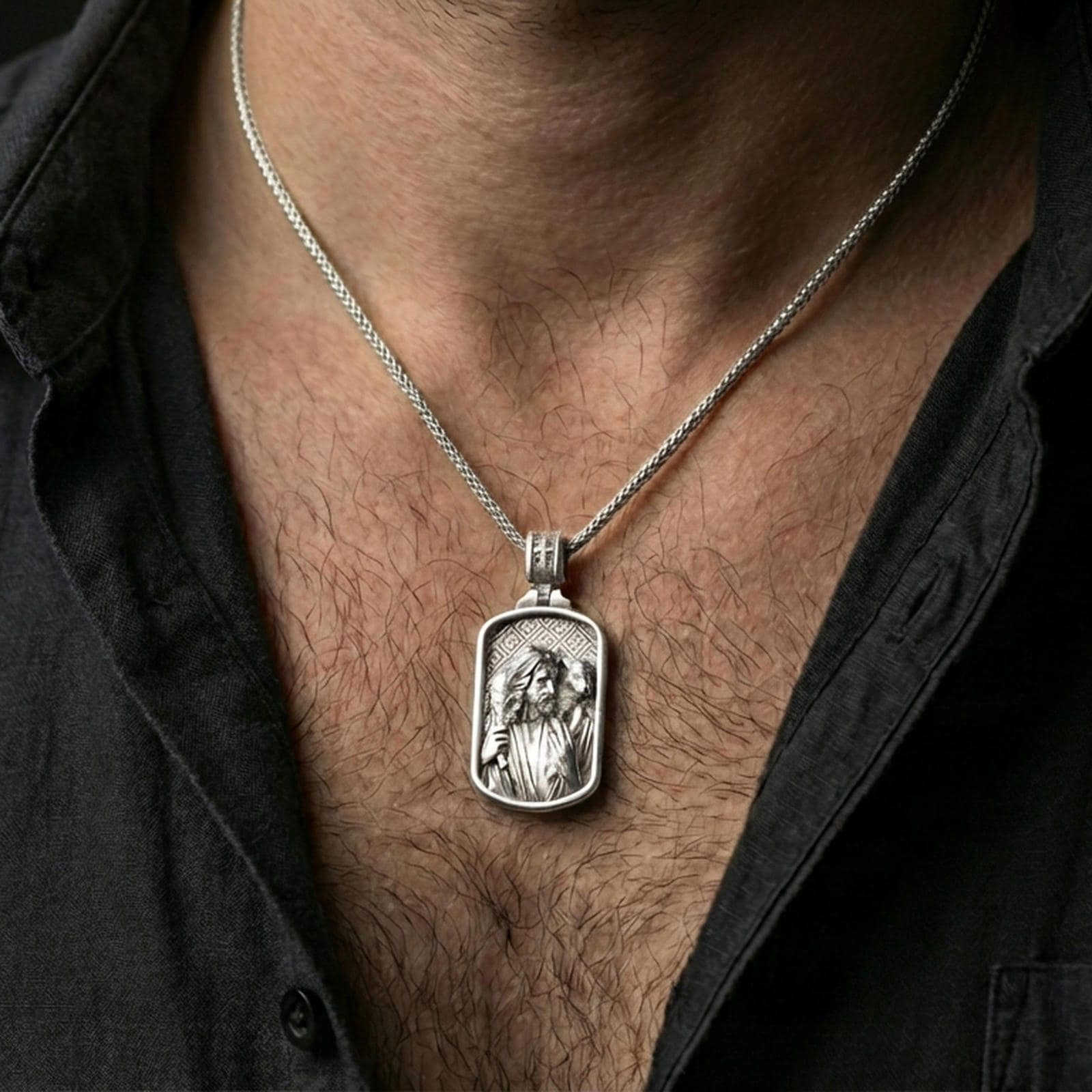 Polished silver Jesus medallion with shepherd relief and lamb detail worn on the neck in a close lifestyle frame, highlighting the sacred portrait and symbolic design