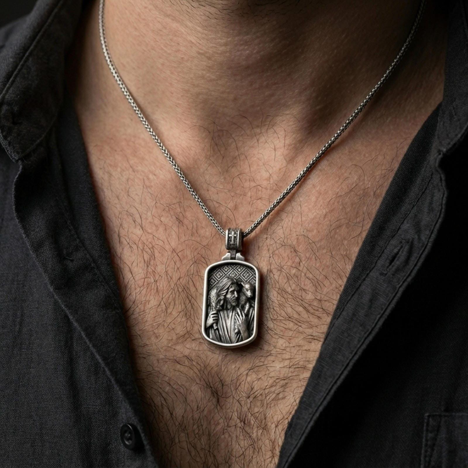 Oxidized Good Shepherd Jesus pendant with lamb over the shoulders worn on the neck in a lifestyle jewelry shot, styled against the chest for a devotional and timeless look