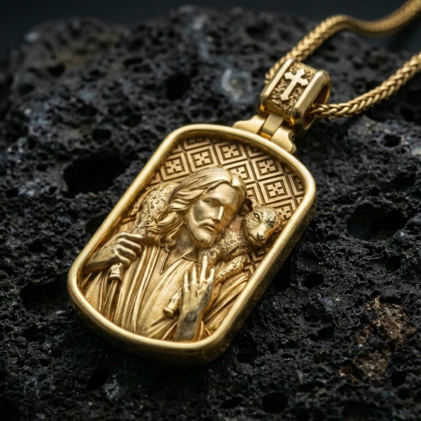 Gold plated Good Shepherd pendant with detailed Jesus portrait, lamb over the shoulders, and engraved geometric background showcased on black volcanic rock in a refined macro jewelry image