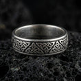 Load image into Gallery viewer, Oxidized Celtic knot band ring on volcanic stone, macro close-up highlighting the darkened recesses and raised interlaced knotwork detail.
