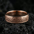 Load image into Gallery viewer, Rose gold plated Celtic knot band ring on volcanic stone, refined close-up with soft rosy highlights and clear interwoven Celtic knot texture.
