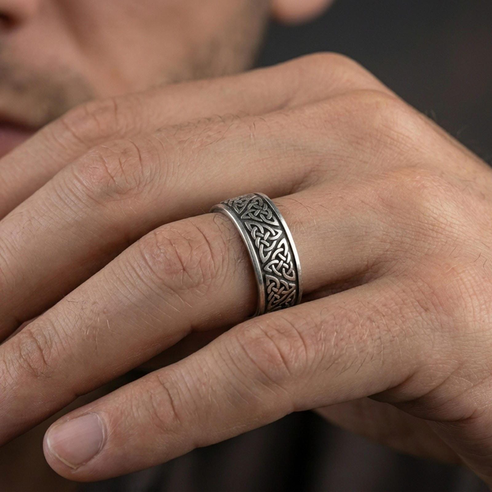 Oxidized Celtic knot band ring worn on a finger, lifestyle wear shot showing antique contrast and the continuous knot pattern at true scale.