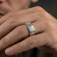 Load image into Gallery viewer, Polished silver Celtic knot band ring worn on a finger, lifestyle photo focusing on bright shine and the raised knotwork texture in natural light.
