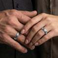 Load image into Gallery viewer, Polished silver woven texture band ring worn on a finger, lifestyle shot focusing on bright shine and the raised woven texture in natural light.
