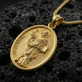 Load image into Gallery viewer, Gold plated Saint Dominic pendant with detailed saint portrait, open book motif, and sacred inscription showcased on black volcanic rock in a refined macro jewelry image

