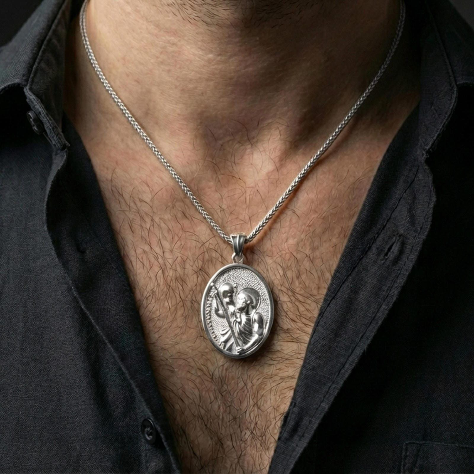 Polished silver Saint Christopher medal with sacred saint relief worn on the neck in a close lifestyle frame, highlighting the oval silhouette and detailed religious design