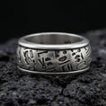 Load image into Gallery viewer, Oxidized sterling silver hieroglyph band ring on volcanic stone, macro close-up highlighting deep-cut Egyptian symbols and matte patina texture.
