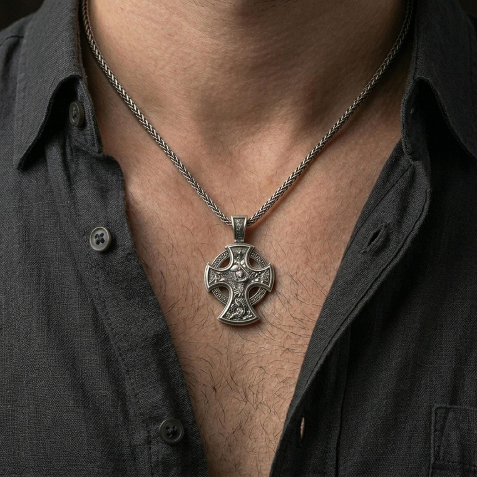 Oxidized Saint Michael cross pendant with winged archangel scene worn on the neck in a lifestyle jewelry shot, styled against the chest for a bold and protective look