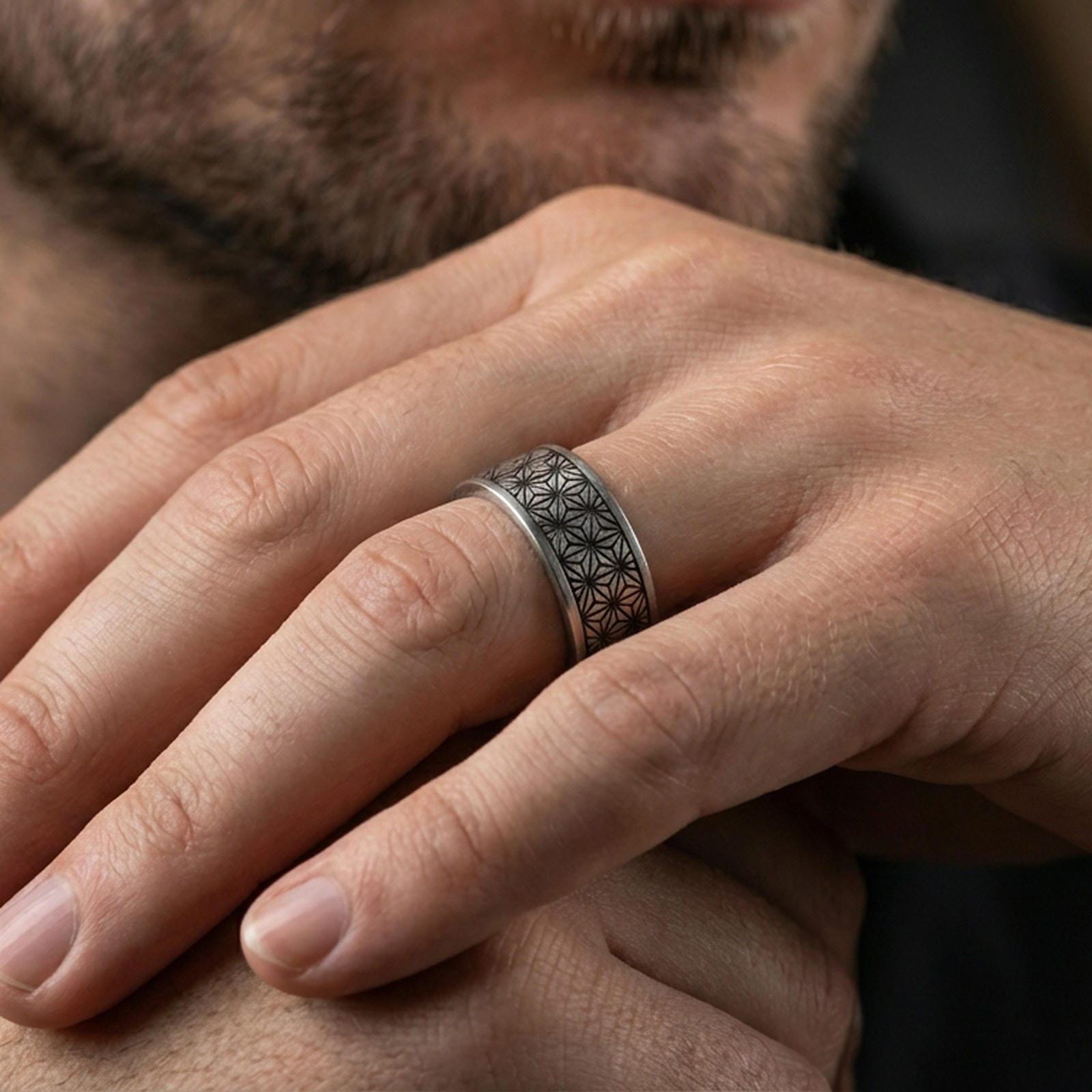 Oxidized sterling silver geometric floral band ring worn on a finger, lifestyle wear photo showing contrast in the engraved pattern and daily fit.