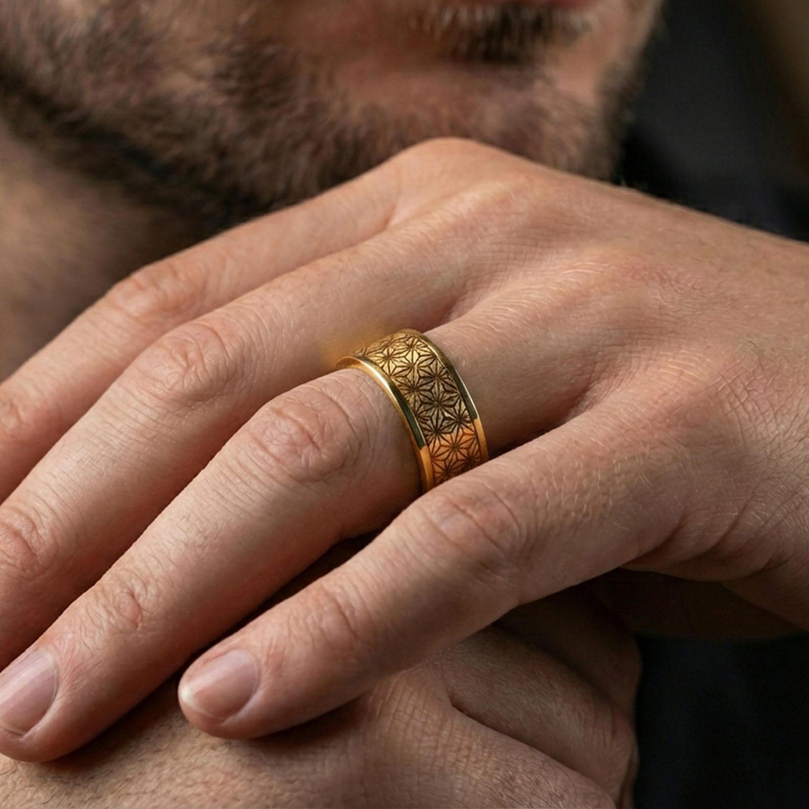 Gold plated geometric floral band ring worn on a finger, lifestyle shot featuring rich gold finish and clear geometric engraving around the band.
