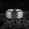 Load image into Gallery viewer, Polished silver geometric floral band ring on volcanic stone, clean product photo emphasizing the sharp repeating star-flower grid and reflective surface.

