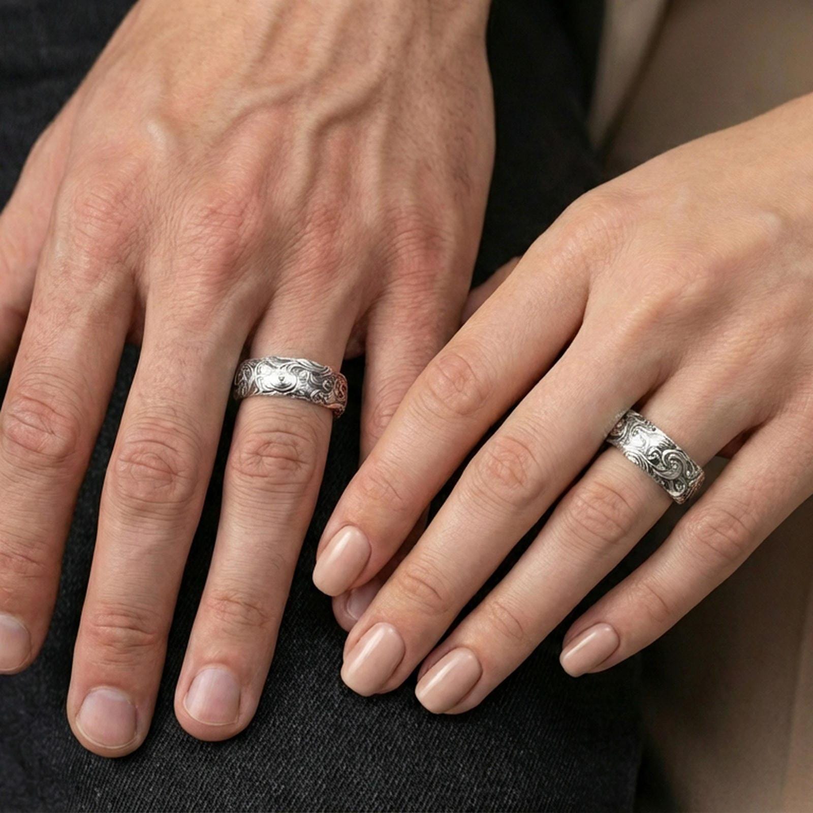 Polished silver scrollwork band ring worn on a finger, lifestyle image capturing reflective finish and engraved scroll details in natural light.