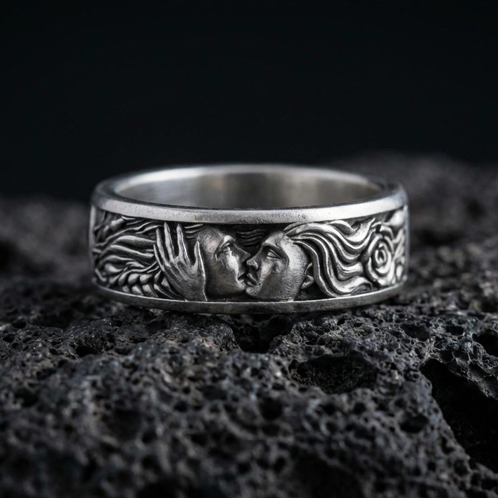 Oxidized sterling silver lovers face ring on volcanic stone, macro close-up highlighting the sculpted couple portrait and dark antique contrast.