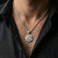 Load image into Gallery viewer, Polished silver Lion of Judah medallion with lion relief and Judah inscription worn on the neck in a close lifestyle frame, highlighting the round coin design and spiritual symbolism
