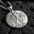 Load image into Gallery viewer, Polished silver Lion of Judah medallion with circular coin design, standing lion relief, and Judah lettering placed on textured volcanic rock in a premium studio product shot
