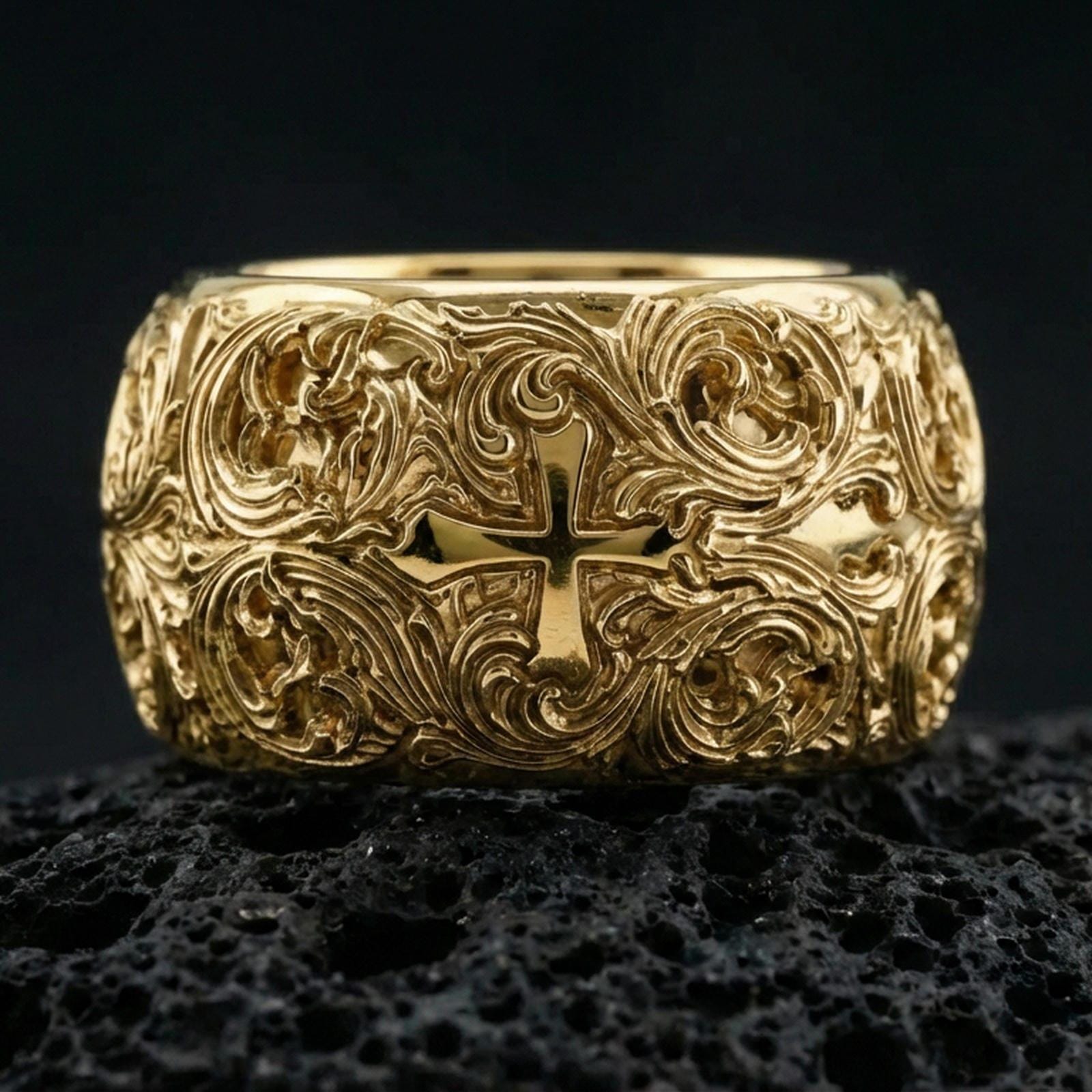 Gold plated ornate cross band ring on volcanic stone, premium close-up showcasing warm gold tone across the raised cross and flowing filigree texture.