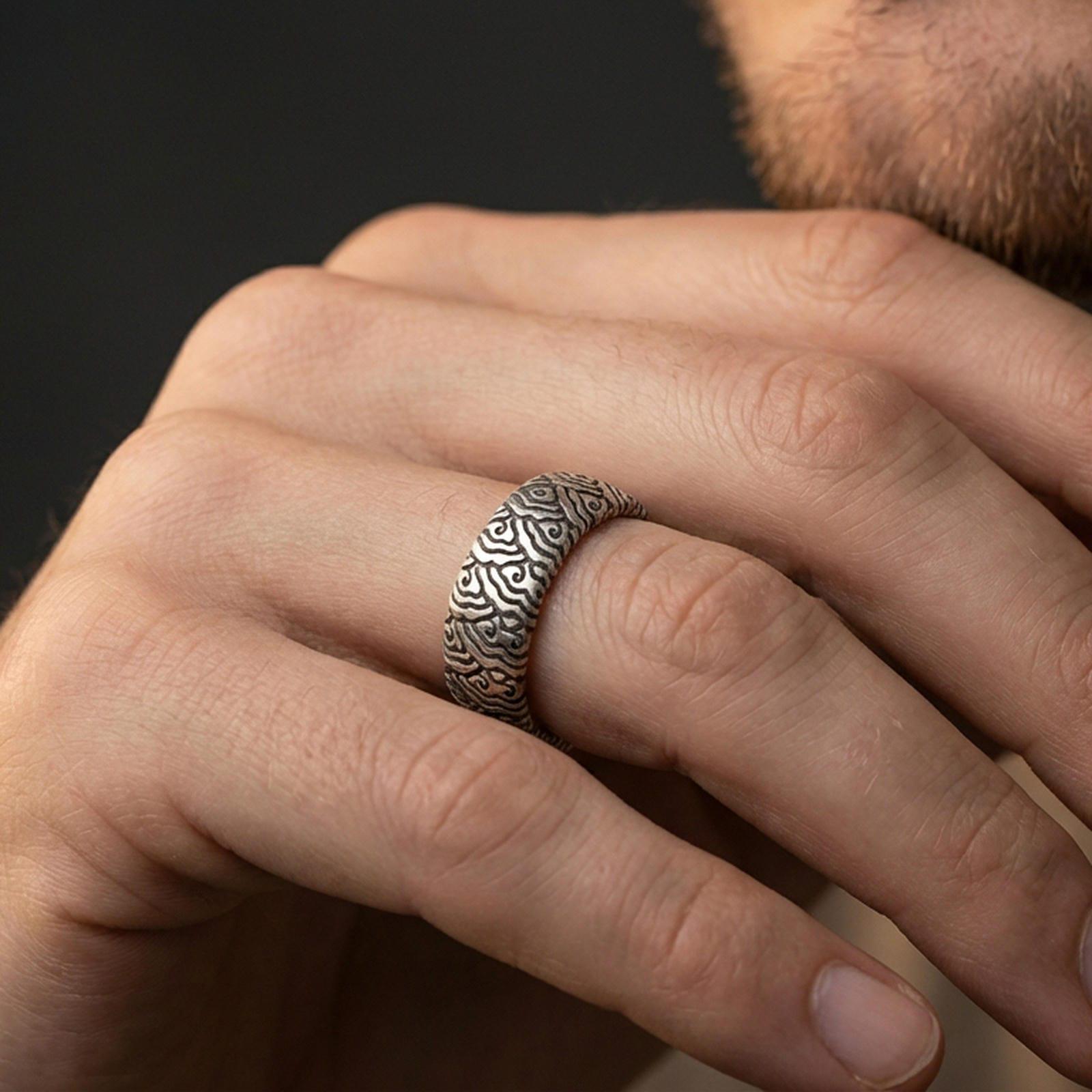 Oxidized sterling silver wave pattern band ring worn on a finger, lifestyle wear image focusing on bold contrast, sculpted texture, and everyday styling.