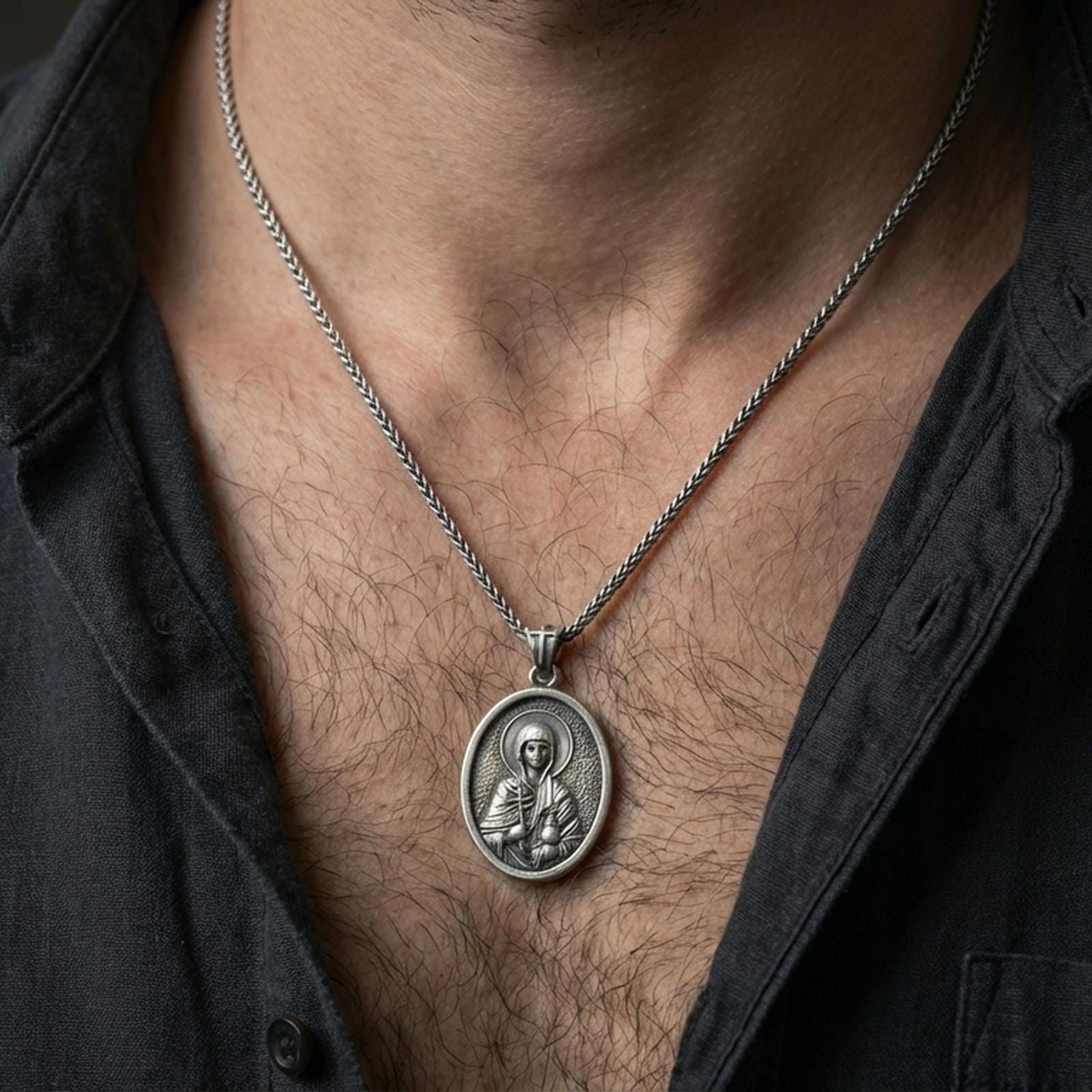 Oxidized Saint Anastasia pendant with haloed saint figure worn on the neck in a lifestyle jewelry shot, styled against the chest for a devotional and timeless look