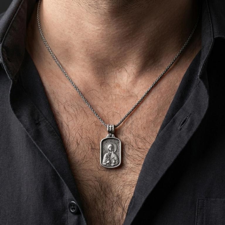 Oxidized Saint Anastasia pendant with haloed saint figure worn on the neck in a lifestyle jewelry shot, styled against the chest for a devotional and timeless look
