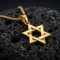 Load image into Gallery viewer, Gold plated Star of David pendant with interwoven hexagram shape, sharp geometric edges, and classic spiritual symbolism showcased on black volcanic rock in a refined macro jewelry image
